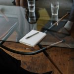 Close-up of a counseling session with two glasses of water and a notepad on a glass table.